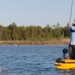 A man fishing from a kayak standing up