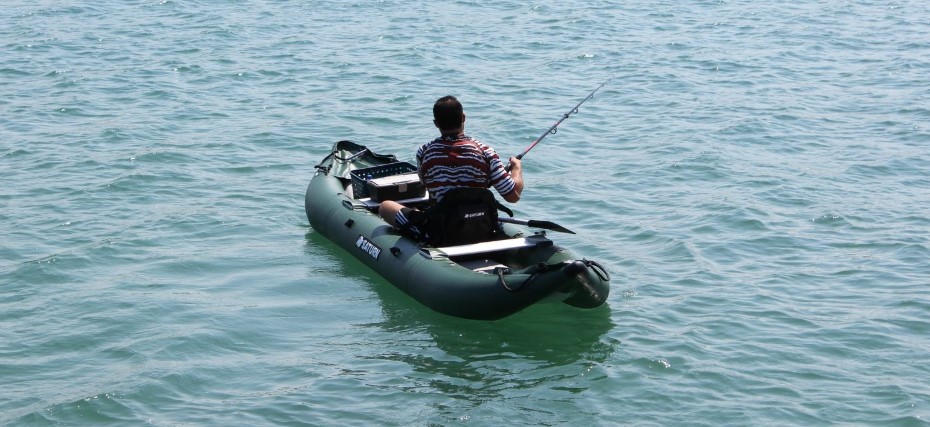 A man with an inflatable fishing kayak on the water